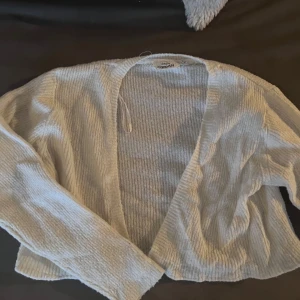 Vit ribbad kofta från KappAhl - Säljer en stilren vit ribbad kofta från KappAhl. Koftan har en öppen design och är perfekt för lager-på-lager-stil. Den är mjuk och bekväm, idealisk för både vardag och mysiga stunder hemma.