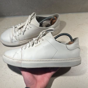 Axel Arigato Skor Herr - Ett par vita stilrena skor från Axel Arigato. Sjukt snygg och har storleken 40 men passar även 41. Har inte lådan till just dessa skor men har en annan Arigato låda hemma om det är nödvändigt. Dem är i använt skick men använda sparsamt! Frågar eller liknande skicka PM!