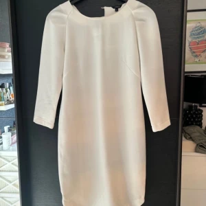 Vit klänning med trekvartsärm - Elegant vit klänning med trekvartsärm och en stilren design. Perfekt för en sofistikerad look.