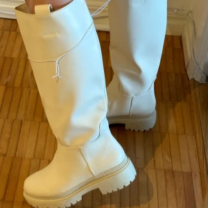 Vita höga stövlar - Snygga vita stövlar med hög skaft och rund tå. Perfekta till vintern. De har en robust sula. Aldrig någonsin använda, helt nya med prislapp kvar. Köpte för 599 kr men säljer för 299 kr. 