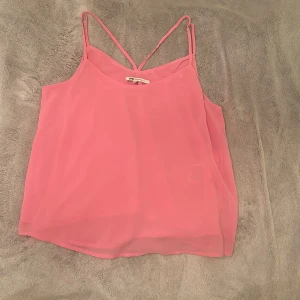 Rosa linnetopp från ONLY - Säljer en söt rosa linnetopp från ONLY med tunna axelband som är justerbara. Perfekt för varma sommardagar. Toppen har en enkel och stilren design.