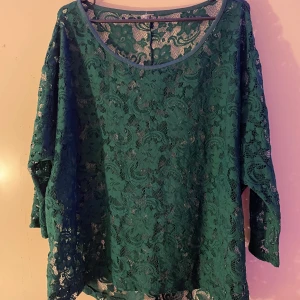 Grön spetsblus - Snygg grön spetsblus med långärmad design och rund hals. Perfekt för att lägga till en touch av elegans till din outfit. Blusen har en lös passform och är tillverkad i ett vackert spetsmaterial.