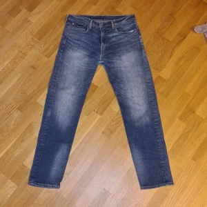 Levi's 502 jeans - Säljer ett par klassiska Levi's 502 jeans i blå denim. De har en straight passform. Det är ett litet hål vid skrevet, se bild.