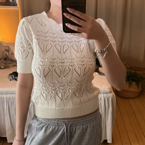 Vit stickad topp - Säljer en söt vit stickad topp med korta ärmar och ett vackert spetsmönster. Helt oanvänd och skulle säga att den är i storlek xs/s