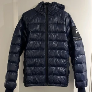 Mörkblå pufferjacka från Peak Performance - Snygg vinter jacka från PeakPerformance. Använts varsamt. Perfekt för kyliga dagar.