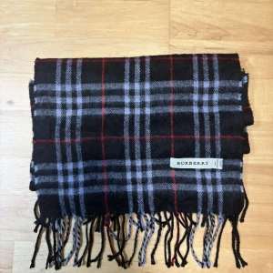 Rutig halsduk från Burberry - Tja! Säljer denna sjukt stilrena halsduken från burberry med rutigt mönster och den mest eftertraktade färgen. Unisex och äkta såklart. Tygmatrial lamull. Längd 153 cm och bredd 30 cm. Tveka inte på att höra av er vid frågor!😁
