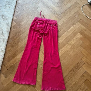 Juicy Couture byxor - Säljer ett par snygga rosa mjukisbyxor från Juicy Couture. Byxorna har en bekväm passform med snörning i midjan och praktiska fickor både fram och bak. Perfekta för en avslappnad stil.