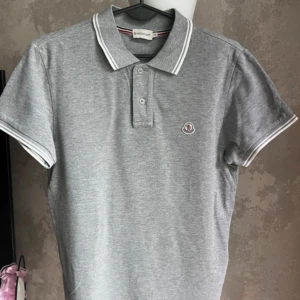 Moncler Polo - Grå Moncler polo shirt. Tröjan är i ett bra skick och använd ett få par gånger.  Storlek S men skulle kunna funka som liten M. Skriv vid minsta fundering!!! Pris kan diskuteras vid snabb och smidig affär. Mvh Edde