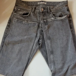 Grå jeans från Zara - Snygga grå jeans från Zara med en klassisk stil. De är i modellen loose fit. Perfekta för en avslappnad stil. De har en knappgylf och bälteshällor för extra funktionalitet. Perfekta att ha till vardags. 