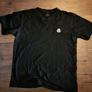 Svart t-shirt från Moncler - Snygg svart t-shirt från Moncler. Den har en klassisk passform med korta ärmar och ett stilrent Moncler-märke på bröstet. Perfekt för en avslappnad och trendig look. Storlek XL men passar som L. Priset går att diskutera