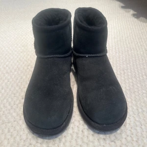 Svarta Uggs - Säljer ett par svarta Ugg i mocka. De har en enkel design med rund tå och är perfekta för kyligare dagar. Ugg insida är fodrad för extra värme och komfort. Använda 2-3 gånger bara.