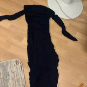 Marinblå långklänning - Elegant mörkblå långklänning med långärmad design. Klänningen har en åtsittande passform och är perfekt för festliga tillfällen. Den mörka färgen ger en sofistikerad look.