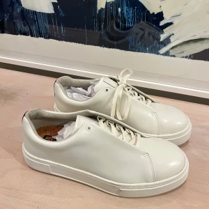 Vita sneakers från eytys - Stilrena vita sneakers från eytys med en lila rand på hälen. Skorna har aldrig använts och orginalpriset var 2200kr