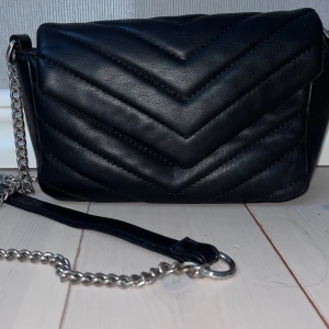 Svart quiltad axelväska med kedja -  Säljer en snygg handväska ifrån glitter, väskan ör i bra skick och har nästan inga tecken på användning💗 nypris 199kr