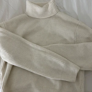 Beige ribbad polotröja från H&M - Säljer en stilren beige polotröja från H&M. Tröjan är ribbad och har långa ärmar, perfekt för kyligare dagar. Den mjuka och bekväma designen gör den till ett mångsidigt plagg i garderoben. Den här köpte jag här om dagen men när jag kom hem insåg jag att jag inte gillade den så aldrig använd.🩷