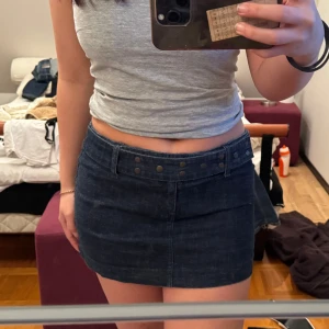 Mörkblå jeanskjol - Säljer en snygg mörkblå jeanskjol med knappar framtill. Kjolen är kort och har en klassisk design som passar perfekt till olika tillfällen. Perfekt för dig som vill ha en stilren look! Priset går att diskutera 