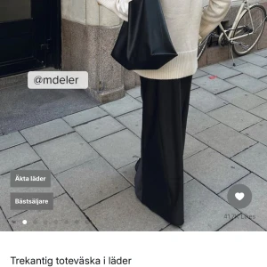 Svart tote i läder - Snygg och stilren svart toteväska i äkta läder. Perfekt för att bära med sig allt man behöver. Väskan har en unik design med en enkel axelrem och en rymlig insida. Helt ny och oanvänd.