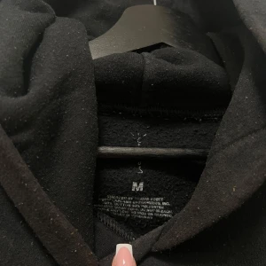 Svart hoodie med tryck - Säljer en svart hoodie från Travis Scott med unikt tryck i vitt på ryggen och ärmen. Perfekt för en avslappnad stil med en edgy touch. Hoodien har en klassisk passform och är tillverkad i mjukt material.
