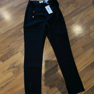 Svarta kostymbyxor från NA-KD - Snygga svarta byxor från NA-KD mef låg midja och slits vid benen. 