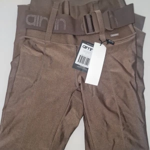 Leggings från Aim'n - Snygga leggings från Aim'n i färgen macchiato med hög midja och ett brett bälte. Perfekta för en stilren look med en bekväm passform. Tillverkade i ett glansigt material som ger en lyxig känsla. Finns inte att köpa längre! Garderobsrensning så kika gärna på övriga auktioner.