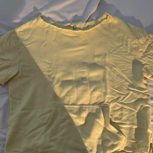 Gul t-shirt med kort ärm - Säljer en enkel gul avklippet t-shirt med korta ärmar. Perfekt för en avslappnad stil. T-shirten har en rund halsringning och är gjord i ett mjukt material. Har klippt en hoodie till en mysig t-shirt