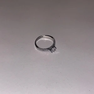 Silverring med glittriga stenar - Elegant silverring prydd med små glittriga stenar längs bandet och en större sten i mitten i mycket bra kvalitet. Perfekt för att ge en touch av glamour till vilken outfit som helst. Köpt på marknad för 1300kr!