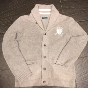 Ralph Lauren Cardigan  - Säljer en varm och mysig Polo Ralph Lauren cardigan I grått. Sparsamt använd och har en stilren design med knappar. Sista bilden representerar färgen lite bättre. Skriv vid minsta fundering 