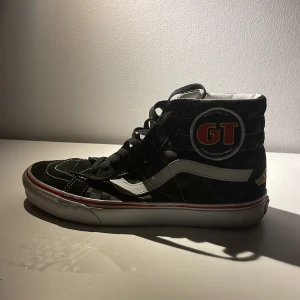 Svarta sneakers med GT-logga - Säljer ett par coola svarta sneakers med hög snörning och GT-logga på sidan. Skorna har en vit sula med röda detaljer och en klassisk vit rand längs sidan. Perfekta för en avslappnad stil med en touch av retro. De är i bra skick och redo för nya äventyr! Storlek 41. Använda fåtal gånger 