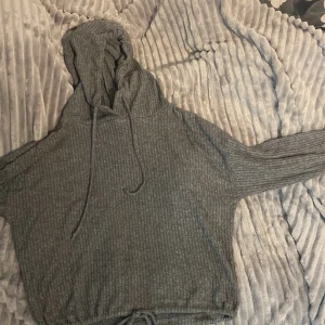 Grå ribbad hoodie från Gina Tricot - Mysig grå hoodie från Gina Tricot i storlek M. Den är ribbad och har en skön luva med dragsko. Perfekt för kyliga dagar när du vill vara både bekväm och stilren. Passar bra till både jeans och mjukisbyxor. 🩶