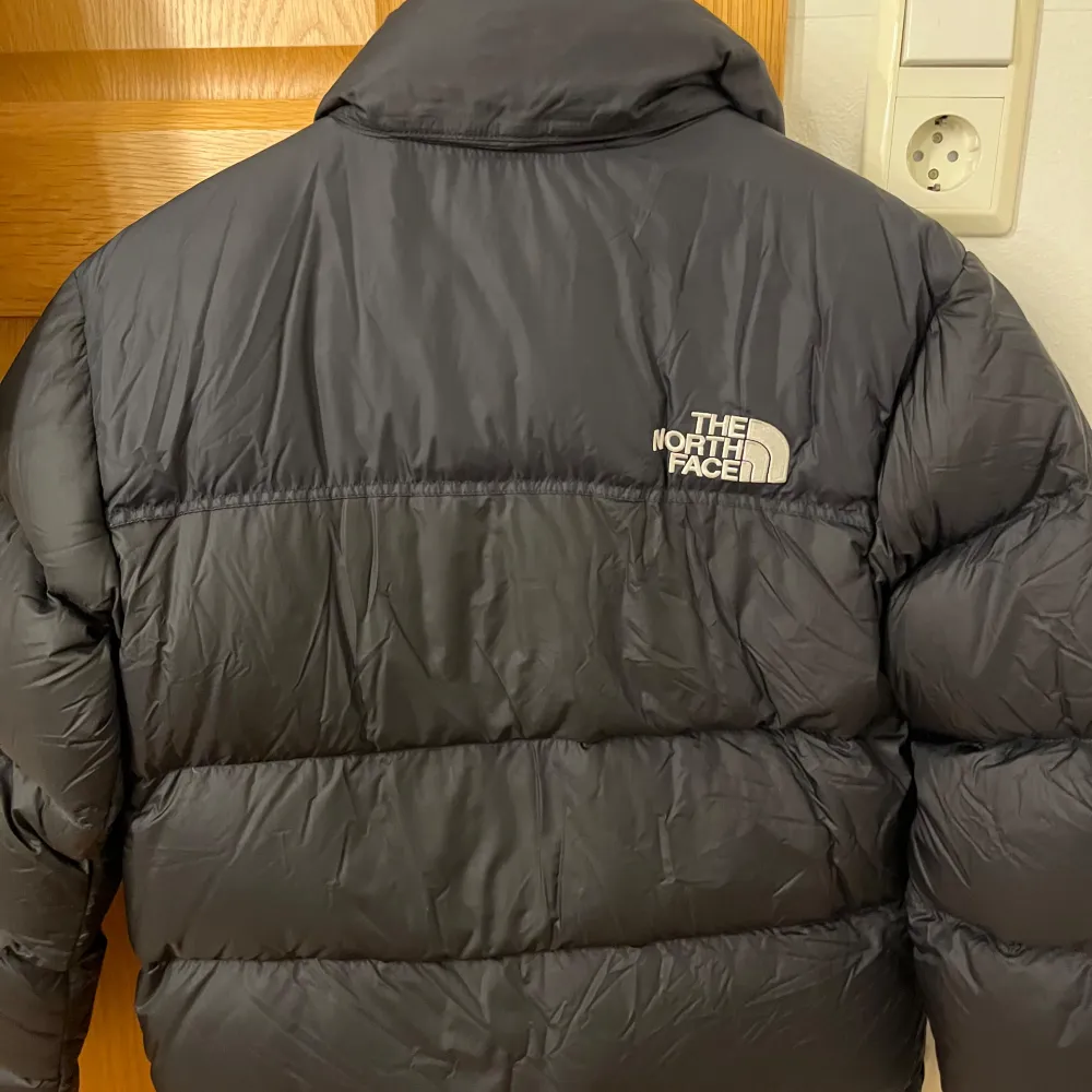 Säljer en snygg och varm svart dunjacka från The North Face. Perfekt för kalla vinterdagar. Jackan har en dragkedja framtill och en hög krage för extra värme. Den är i mycket bra skick och har en klassisk pufferstil. Passar perfekt för både vardag och utomhusaktiviteter.. Takit.