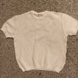 Vit stickad kortärmad tröja - Säljer en superfin vit stickad tröja med korta ärmar. Perfekt för vår och sommar! Den har en luftig och bekväm passform, vilket gör den idealisk för varmare dagar. Tröjan är i mycket bra skick och redo för en ny ägare. Passar perfekt till jeans eller kjol för en avslappnad look.