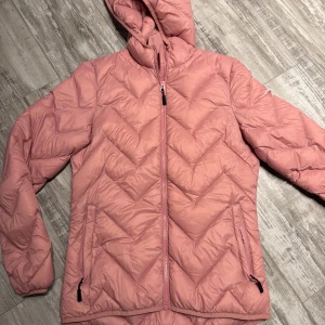 Rosa dunjacka från Cross Sportswear - Säljer en superfin rosa dunjacka från Cross Sportswear i storlek S. Jackan är quiltad och har en dragkedja framtill samt två fickor med dragkedjor. Perfekt för kyliga dagar med sin varma och sköna passform. Inte jätte tjock jacka. Huvan ger extra skydd mot väder och vind. 🧥💖