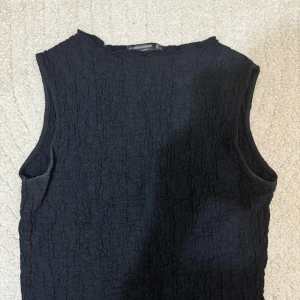 Svart ärmlös topp från Stradivarius - Säljer en stilren svart ärmlös topp från Stradivarius i storlek S. Toppen har en texturerad yta som ger den en unik look. Perfekt för både vardag och fest! 🖤