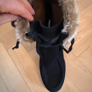 Svarta boots med pälsdetalj Filippa K - Snygga svarta boots med hög klack och mysig pälsdetalj runt skaftet. Perfekta för vintern och hösten när du vill hålla dig varm och stilren. De har snörning framtill för en justerbar passform. Från Felippa K