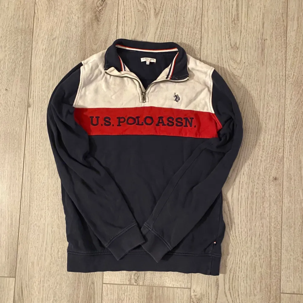 Säljer en snygg quarterzip tröja från U.S. Polo Assn. i blått och vitt med en röd rand och logga på bröstet. Tröjan har en dragkedja vid halsen och är perfekt för både vardag och avslappnade tillfällen. Passar bra till jeans eller chinos!. Hoodies.