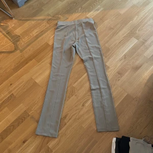 Beige byxor med slits - Snygga beige byxor i ett mjukt material. De har en stilren design med slits vid bensluten som ger en modern touch. Perfekta för både vardag och fest! 🕺