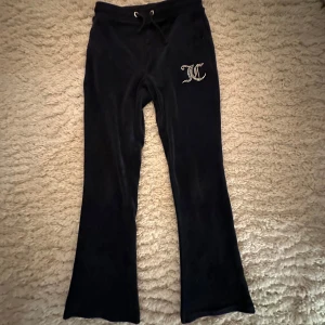Mörkblå mjukisbyxor från Juicy Couture barn - Säljer ett par svarta mjukisbyxor från Juicy Couture i storlek 9/10. Byxorna har en glittrig logga på ena benet. Superbekväma och stiliga! ✨