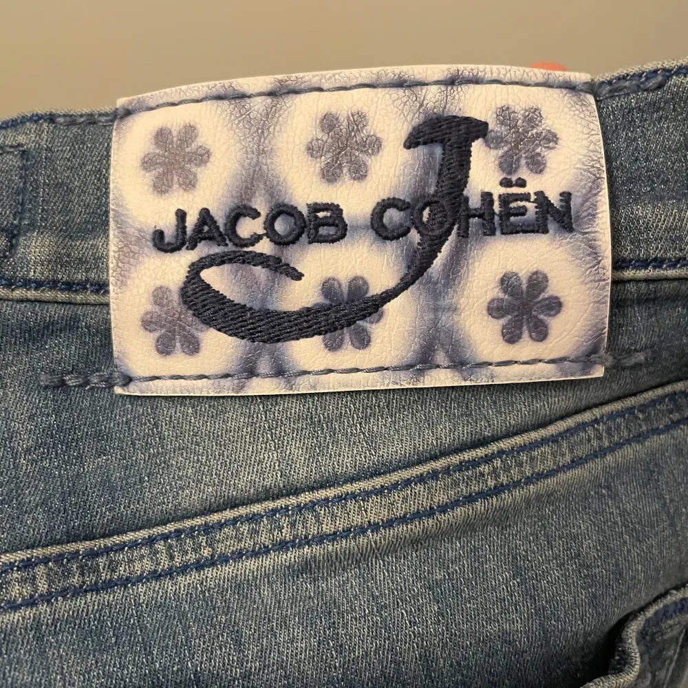 Säljer ett par snygga blå jeans från Jacob Cohën. De är handgjorda och har en lyxig känsla. Jeansen har en tight passform och är perfekta för både vardag och fest. Märkesdetaljer finns på baksidan och insidan av midjan. Passar perfekt för dig som vill ha stil och komfort i ett!. Jeans & Byxor.