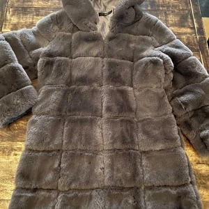 Grå fuskpäls, stl L - Säljer en supermjuk, varm och lyxig grå pälsjacka från Realty, som känns helt äkta. Perfekt för kalla vinterdagar med sin fluffiga och varma design. Kappan är av halvlång modell med mysig luva som ger en stilren look som passar både till vardags och fest. Den är i mycket bra skick och redo att hålla dig varm och snygg hela säsongen! 🐻❄️