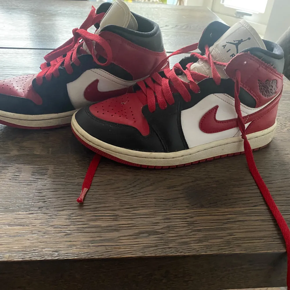 Säljer ett par klassiska Nike Air Jordans i rött, svart och vitt. Skorna har en snygg design med snörning och den ikoniska Air Jordan-loggan på sidan. Perfekta för både vardag och fest! 🏀. Skor.