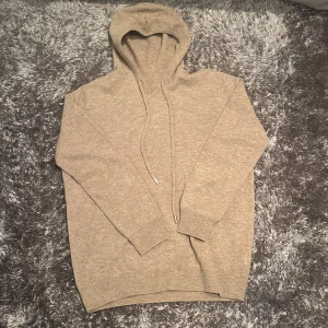 Beige Cashmere - Säljer en supersnygg beige hoodie i cashmere. Perfekt för kyliga dagar med sin mjuka och bekväma passform. Den har en klassisk design med dragsko i huvan och långa ärmar. Passar både till vardags och för en avslappnad stil ”pris går även att diskuteras lite vid snabb affär” Anledning till det låga pris är för att det inte finns någon tag kvar vart man kan se vilket märke det är
