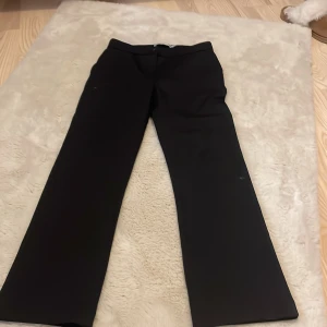 Svarta kostymbyxor från lager157  - Säljer ett par klassiska svarta kostymbyxor i storlek 140. De har en stilren design med knapp och dragkedja framtill. Perfekta för både formella och vardagliga tillfällen. Byxorna är i bra skick och redo för en ny ägare!