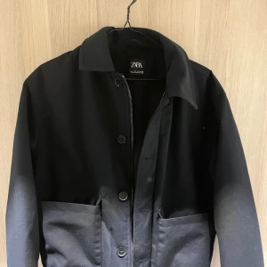 Svart jacka från Zara - Säljer en varsamt använd jacka från Zara. Den har en klassisk krage och stängs med både dragkedja och knappar. Perfekt för höst och vår, med praktiska fickor framtill. Jackan är i mycket bra skick och passar till många olika outfits.