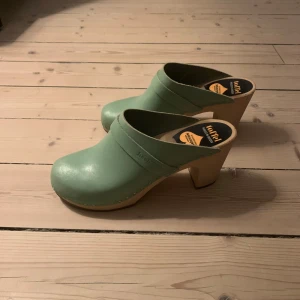 Gröna träskor med klack från Swedish hasbeens - Fina mintgröna träskor med klack från Swedish hasbeens. Storlek 39. Använda men i gott skick. Skickar gärna fler bilder vid förfrågan. 