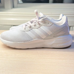 Vita sneakers från Adidas - Snygga vita sneakers från Adidas med klassisk design och bekväm Cloudfoam-sula. Skorna har snörning och är tillverkade i syntetmaterial med meshdetaljer för extra andningsförmåga.