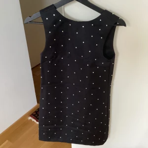 Klänning från HM - Säljer denna jättefina klänningen från H&M, som bara används en gång så den är i super bra skick! Den har små kristaller på sig och har en öppen rygg med rosett. Ganska dåliga bilder men skriv om ni vill ha mer. 