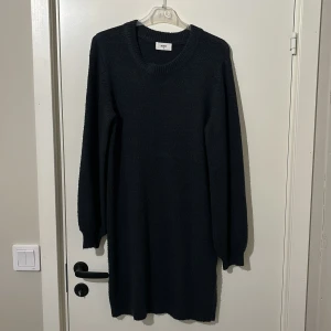 Mörkblå stickad klänning från Object - Snygg mörkblå stickad klänning från Object med långa ärmar och rund halsringning. Perfekt för kyligare dagar med sin mysiga och stilrena design. Klänningen har en enkel och tidlös look som passar till många tillfällen.