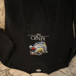 Svart tröja från Kenzo - Säljer en svart tröja från Kenzo med ett färgglatt tigertryck på framsidan. Tröjan har långa ärmar och en rund halsringning. Perfekt för en stilren och trendig look. Min kamera är trasig därför är bilden upp och ner ☺️