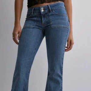Blå low waist bootcut jeans - Snygga blå bootcut jeans från Nelly med låg midja och framträdande fickdetaljer, i storlek 32. Säljer de då de inte kommer till användning, använt ett fåtal gånger de är fortfarande som nya. Original pris 699kr