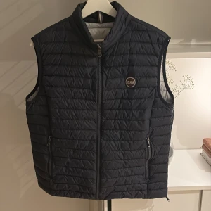 Svart quiltad dunväst från Colmar - Snygg svart quiltad dunväst från Colmar med dragkedja framtill och två praktiska fickor med dragkedjor. Perfekt inför våren.